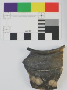 Picture showing a ceramic sherd, ca 6 cm big next to a length/colour scale