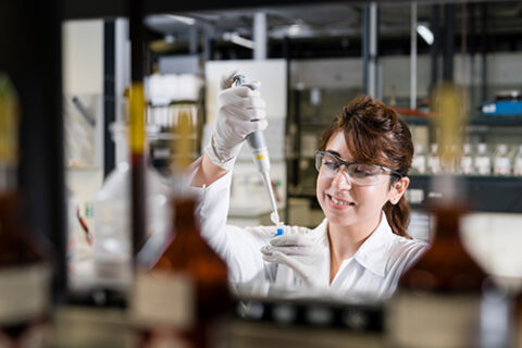 The image shows a young woman working at a food chemistry laboratory.