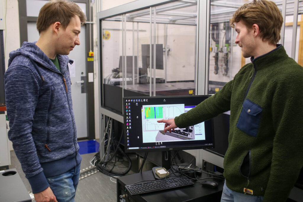 Dominik Thiel (l.) und Phillip Greißel untersuchen in ihrem Laserlabor was mit Molekülen passiert, wenn man sie mit Licht anregt. (Foto: Gerd Gätzschmann / FAU)